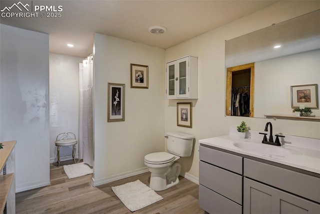 bathroom featuring vanity, wood finished floors, toilet, and baseboards