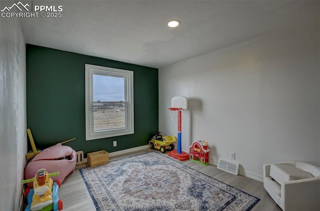 recreation room featuring visible vents, baseboards, and wood finished floors