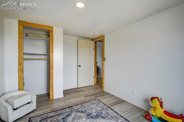 bedroom with a closet, baseboards, wood finished floors, and recessed lighting