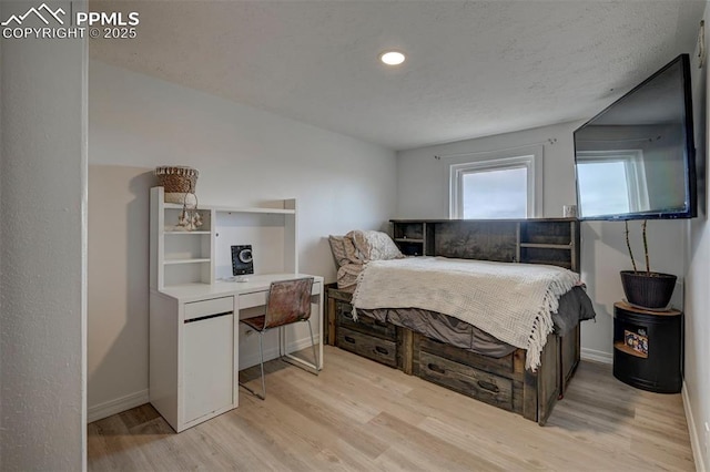 bedroom with a textured ceiling, light wood-style flooring, and baseboards