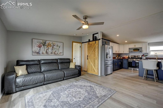 living room with a barn door, light wood-style flooring, a ceiling fan, and recessed lighting