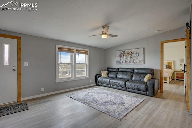 living room featuring a ceiling fan, light wood-type flooring, vaulted ceiling, and baseboards