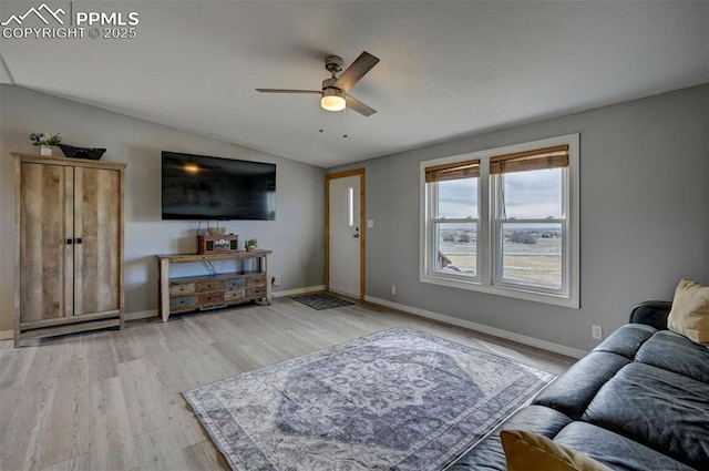 living room featuring lofted ceiling, light wood-style flooring, baseboards, and ceiling fan