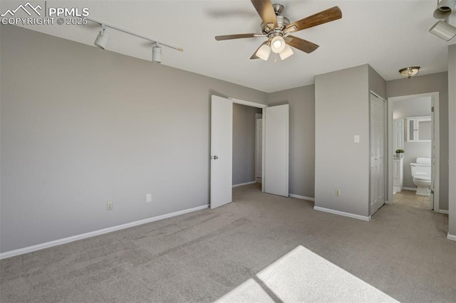 unfurnished bedroom with carpet flooring, ceiling fan, baseboards, and ensuite bathroom