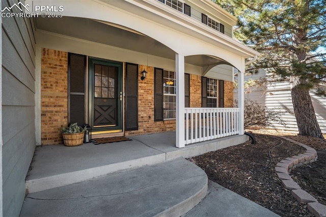 property entrance with covered porch and brick siding