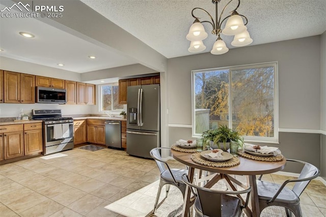 kitchen with brown cabinets, appliances with stainless steel finishes, light countertops, and pendant lighting