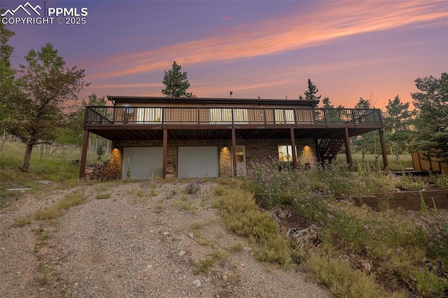 view of front facade with gravel driveway, an attached garage, and a deck