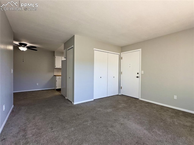 unfurnished bedroom featuring dark carpet, baseboards, and two closets