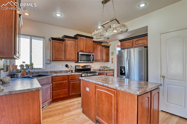 kitchen with light wood-style flooring, appliances with stainless steel finishes, a center island, a sink, and recessed lighting