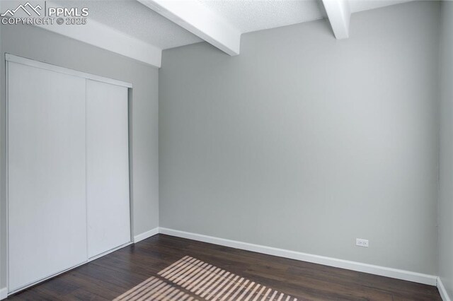 9995 E Harvard Ave Unit 155, Denver, CO 80231 - unfurnished bedroom with a textured ceiling, beamed ceiling, dark wood finished floors, and baseboards