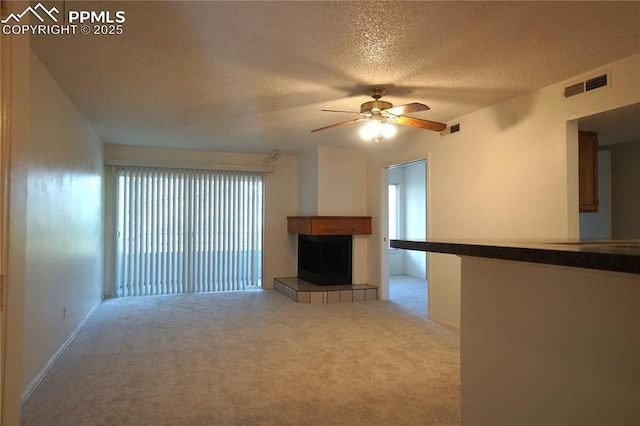 unfurnished living room featuring a healthy amount of sunlight, visible vents, and a tiled fireplace