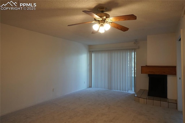 unfurnished living room featuring carpet floors, a ceiling fan, a textured ceiling, and a tile fireplace