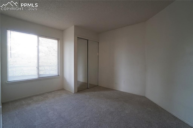 unfurnished bedroom featuring carpet floors, a closet, and a textured ceiling