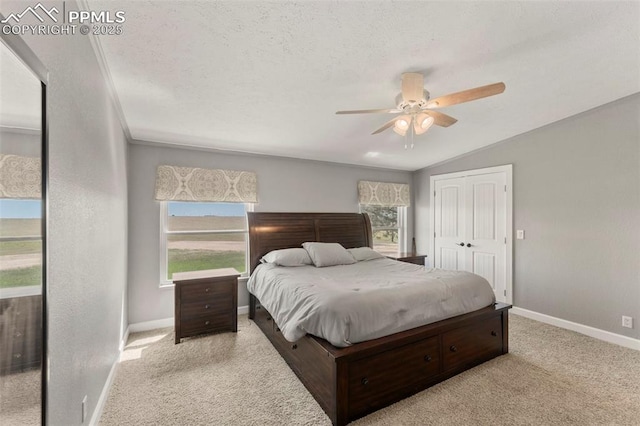 carpeted bedroom with baseboards, ceiling fan, vaulted ceiling, a textured ceiling, and a closet