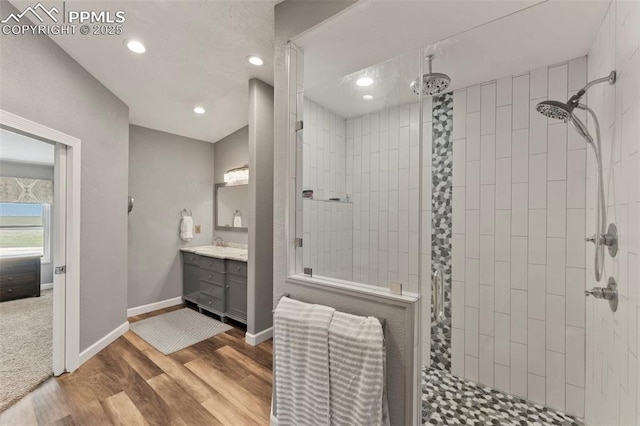 full bathroom with recessed lighting, wood finished floors, vanity, baseboards, and tiled shower