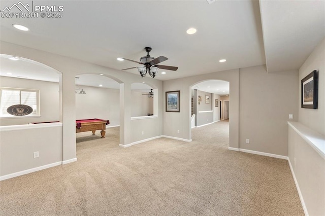 carpeted empty room featuring baseboards, arched walkways, a ceiling fan, and recessed lighting