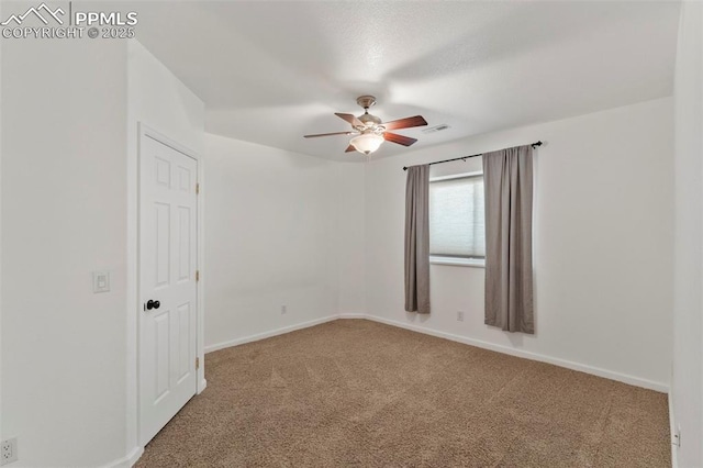 carpeted empty room featuring a ceiling fan, visible vents, and baseboards