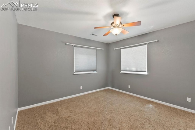 empty room featuring ceiling fan, carpet, visible vents, and baseboards