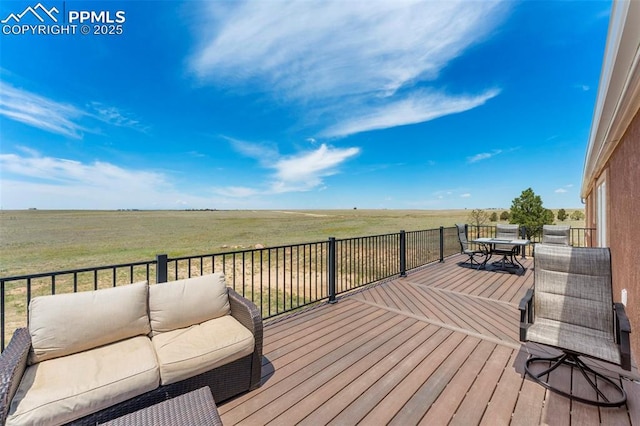 deck with outdoor dining area, a rural view, and an outdoor hangout area