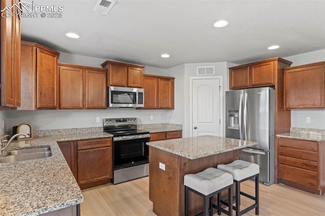 kitchen with appliances with stainless steel finishes, light wood-style floors, visible vents, and a sink