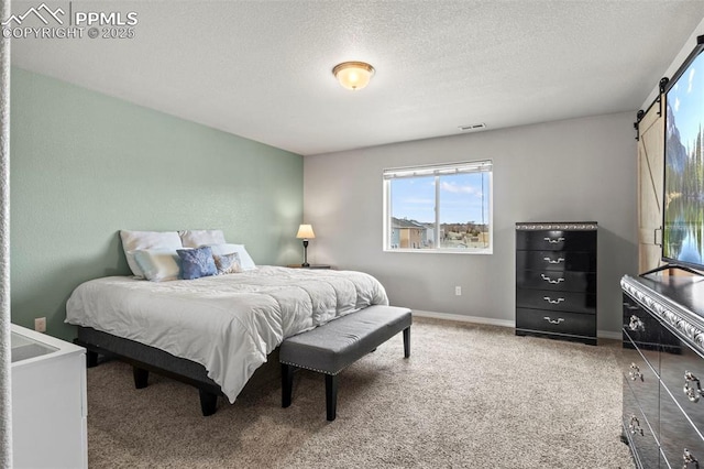 carpeted bedroom featuring a textured ceiling, a barn door, visible vents, and baseboards