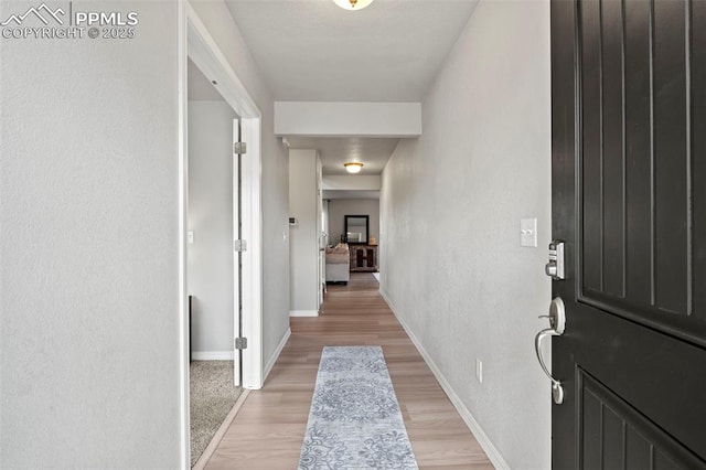 interior space featuring light wood-type flooring, baseboards, and a textured wall