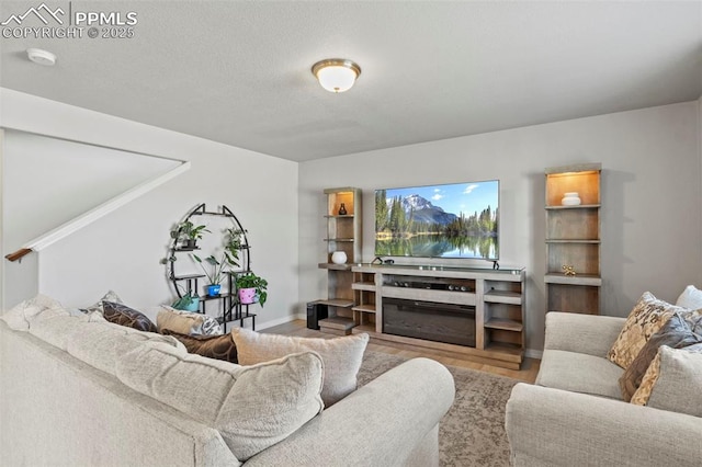 living room with a textured ceiling, wood finished floors, and baseboards