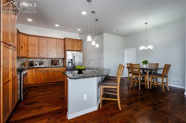 kitchen featuring appliances with stainless steel finishes, brown cabinetry, and dark wood finished floors