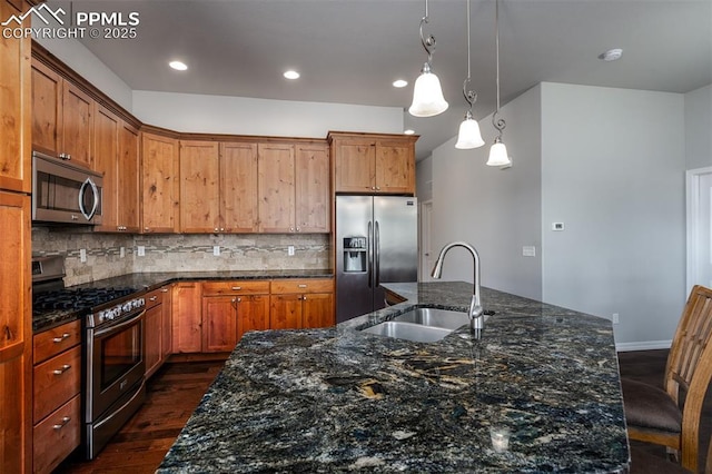 kitchen with dark wood-style flooring, pendant lighting, stainless steel appliances, backsplash, and a sink