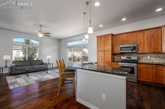 kitchen featuring plenty of natural light, decorative backsplash, appliances with stainless steel finishes, brown cabinets, and a sink