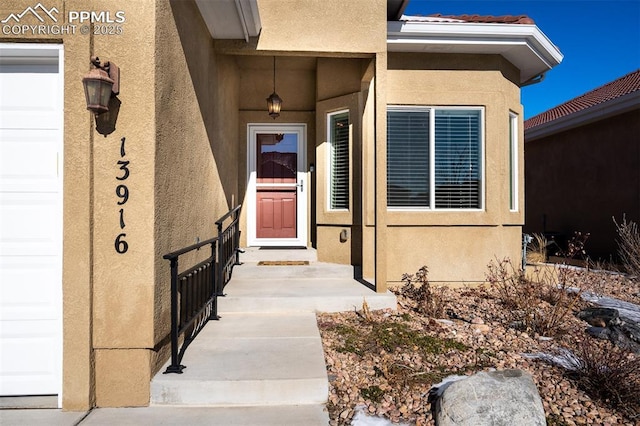 entrance to property with a garage and stucco siding