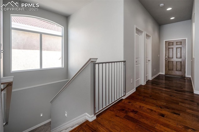 hall with recessed lighting, baseboards, dark wood finished floors, and an upstairs landing