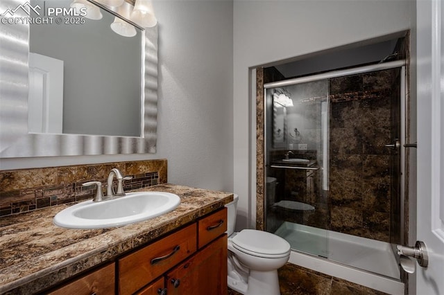 bathroom with backsplash, a shower stall, toilet, and vanity