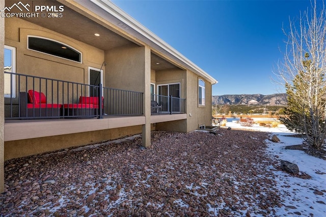 snow covered property with a mountain view and stucco siding