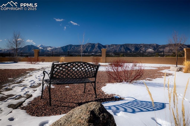 snowy yard with fence and a mountain view