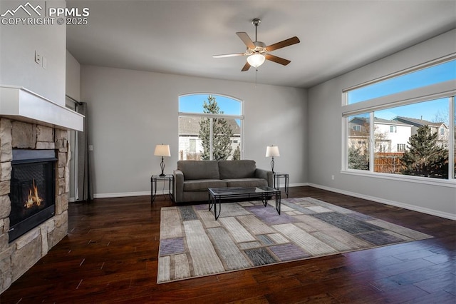 living area with a ceiling fan, a fireplace, hardwood / wood-style flooring, and baseboards