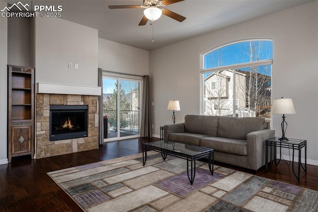 living area with ceiling fan, a fireplace, baseboards, and wood finished floors