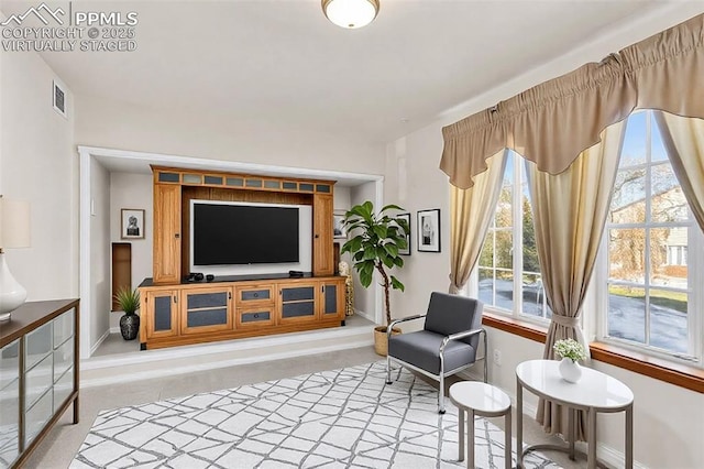 living area featuring visible vents, light carpet, and baseboards