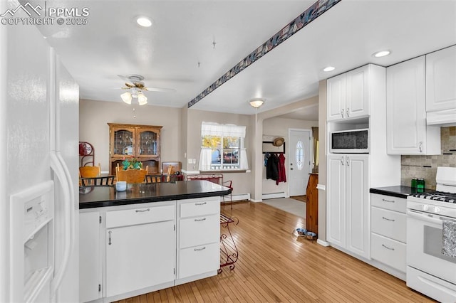 kitchen featuring white appliances, white cabinetry, light wood-style floors, decorative backsplash, and dark countertops