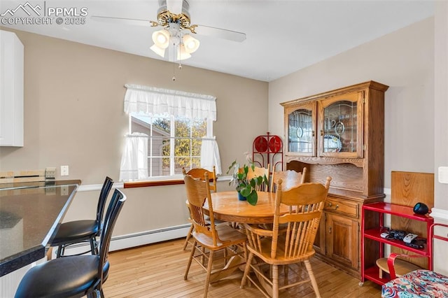 dining area featuring a baseboard radiator, light wood-style flooring, and a ceiling fan