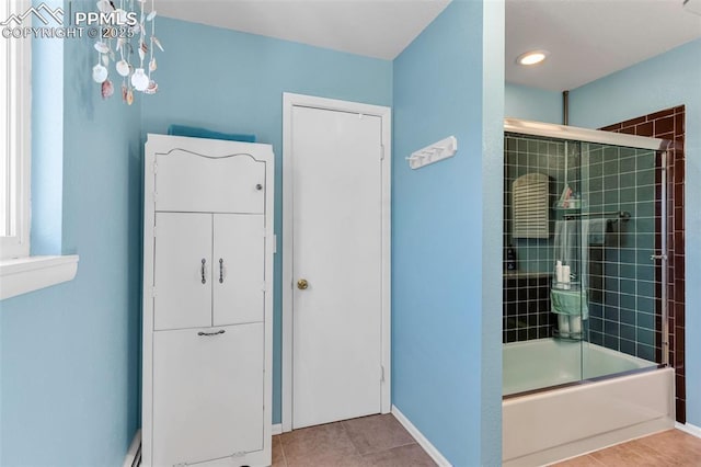 bathroom featuring enclosed tub / shower combo, tile patterned flooring, and baseboards