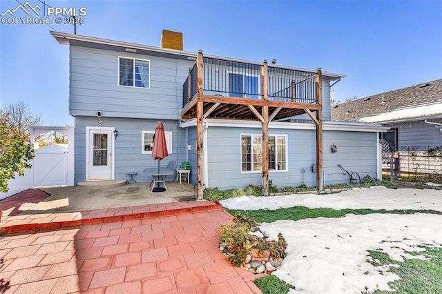 rear view of house featuring a chimney, a patio area, fence, and a gate