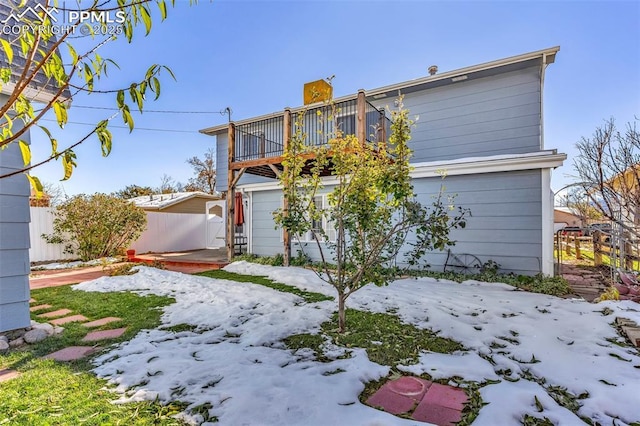 rear view of house featuring a garage and fence