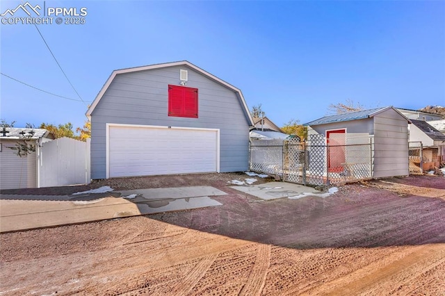 detached garage featuring fence and a gate