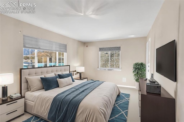 bedroom with light carpet, multiple windows, and baseboards