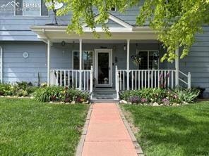 doorway to property featuring covered porch and a lawn