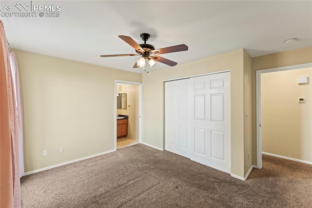 unfurnished bedroom with a closet, ensuite bathroom, carpet flooring, ceiling fan, and baseboards