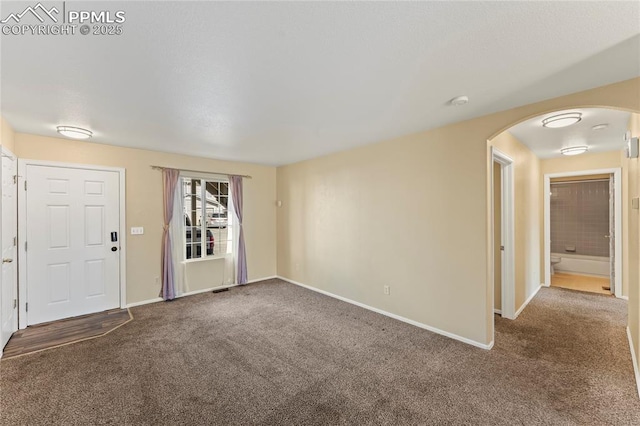 interior space featuring arched walkways, carpet flooring, and baseboards