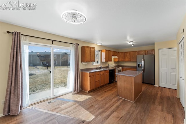 kitchen featuring white electric stove, visible vents, dark wood finished floors, stainless steel fridge with ice dispenser, and a sink