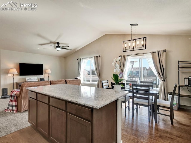 kitchen with pendant lighting, dark wood finished floors, lofted ceiling, open floor plan, and a kitchen island